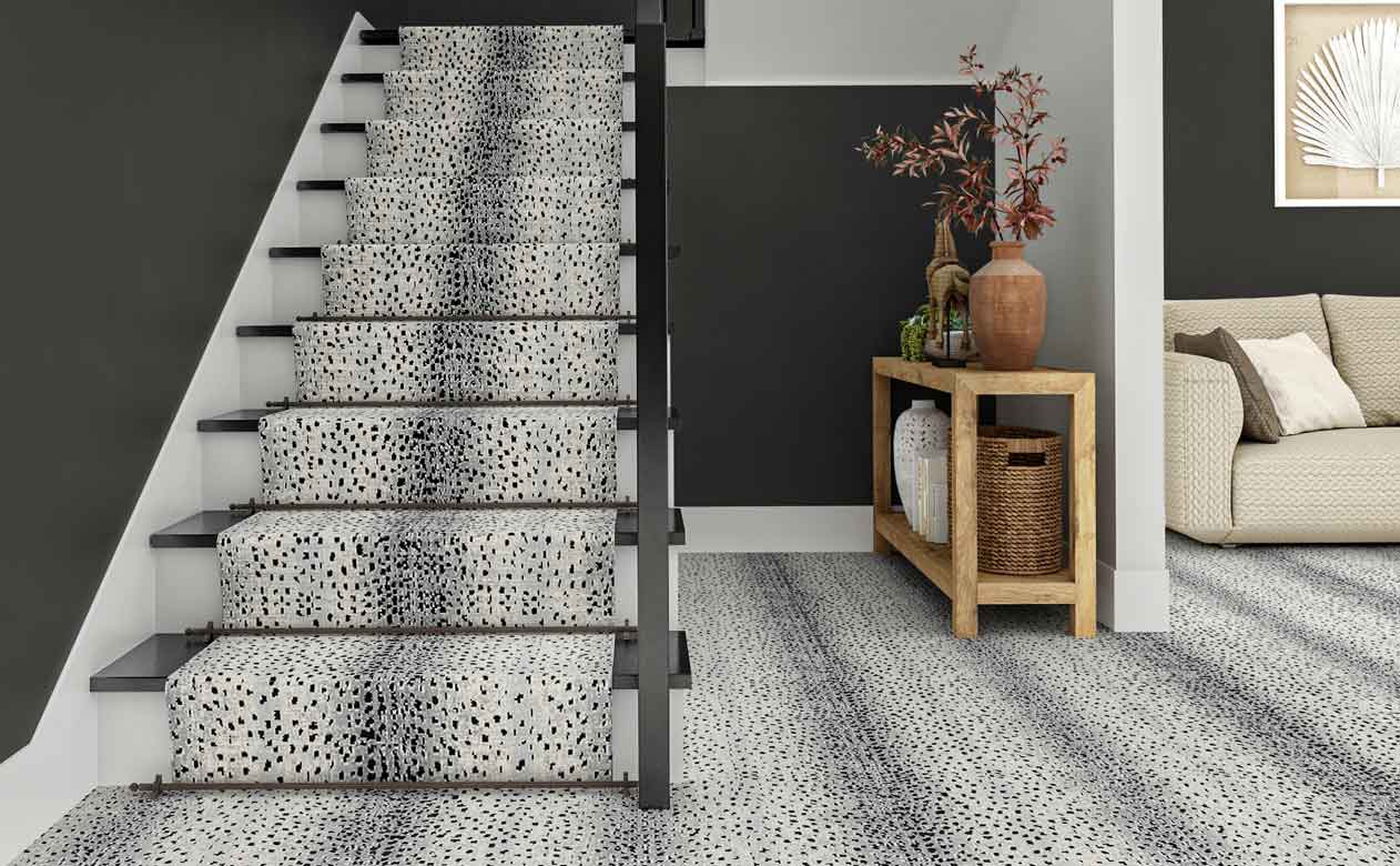 animal print carpeted staircase and modern entryway with styled entry table and gray walls